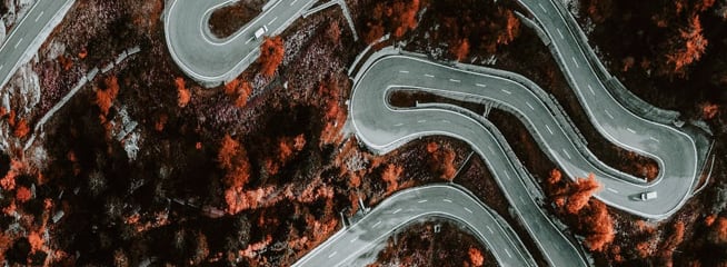 Aerial view of winding mountain roads surrounded by autumn foliage.