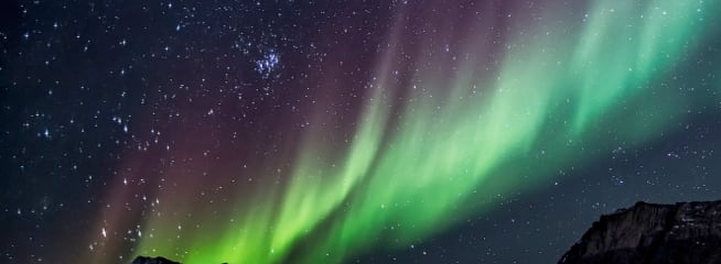 Vibrant aurora borealis dancing in the night sky filled with stars.